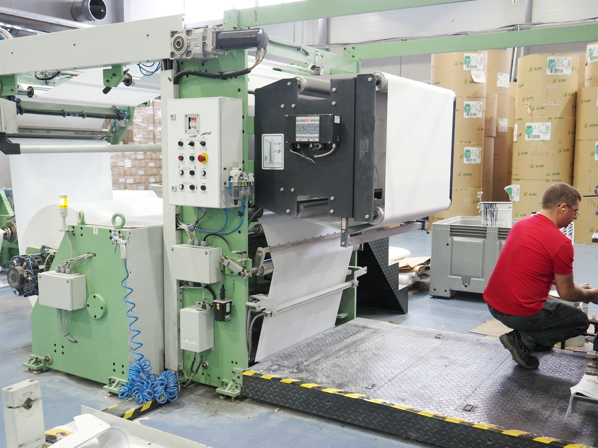 Рабочий линии, настраивающий подачу бумажного полотна после запуска нового бумажного роля